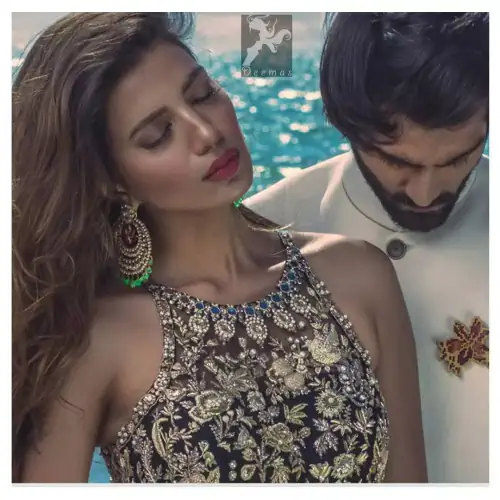 Charade net peplum having halter neckline. Peplum adorned with light golden, pearls and mix embellishment. Husk net sharara and dupatta.