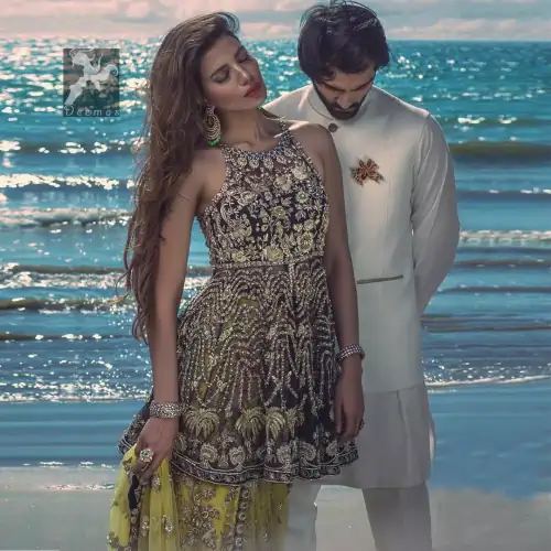 Charade net peplum having halter neckline. Peplum adorned with light golden, pearls and mix embellishment. Husk net sharara and dupatta.