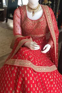 Simple but elegant deep red bridal blouse having dull golden and light antique embellishment. Appliqued with bright red fabric. Red lehengha having large borders of hand embellishment and small motifs spray above the hemline. Same border as on lehengha has been implemented on dupatta with motifs spray all over it.