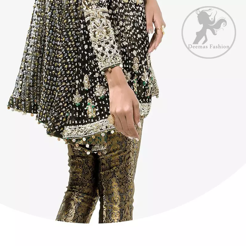 This classic forest black peplum style shirt meticulously highlighted with dull golden kora, dabka ,tilla, sequins and pearls. It has silhouettes  and cutwork on sleeves.It is adorned with V-Shaped neckline. Its full sleeves are fully embroidered. This shirt is decorated with small and large sized floral motifs. It comes with brocade capri pants and beautifully decorated with forest black dupatta having sprinkled sequins all over it.
