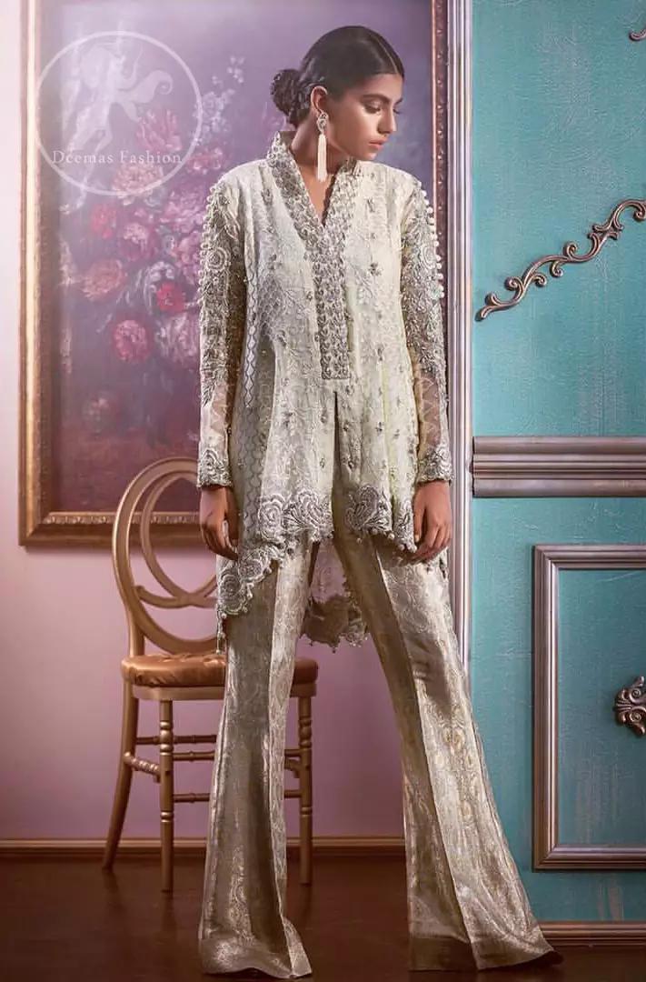 This open short shirt is decorated with resham thread, kora, dabka, tilla, sequins and pearls. It is self embroidered shirt embellished with floral thread embroidery. Sleeves are fully embroidered. it is further enhanced with embroidered scalloped border which adds to the look. It comes with brocade bell shaped pants. It is beautifully coordinated with chiffon dupatta which is sprinkled with sequins all over.

