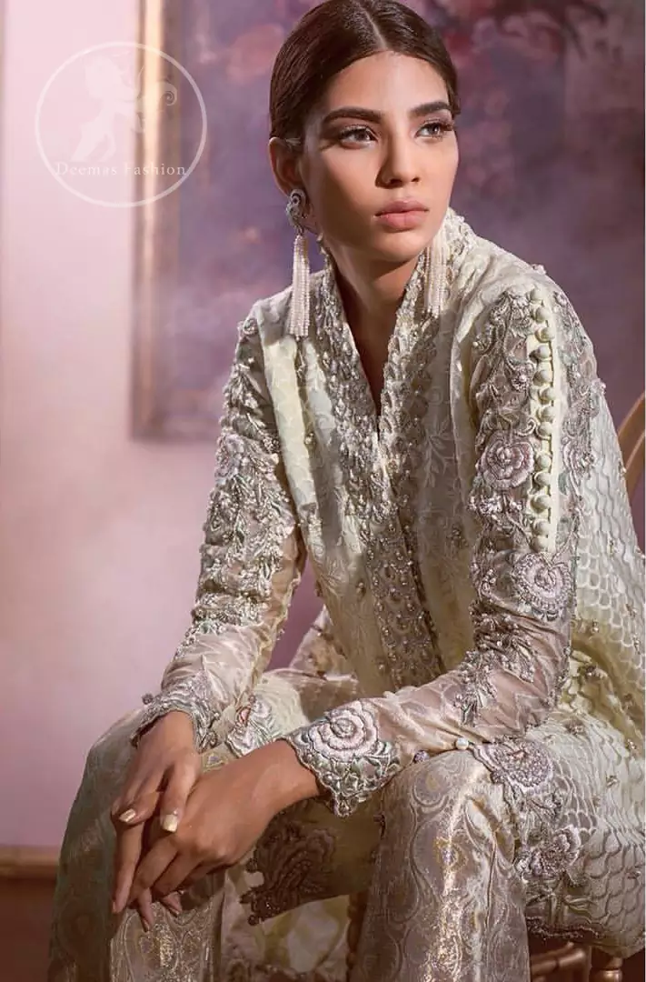 This open short shirt is decorated with resham thread, kora, dabka, tilla, sequins and pearls. It is self embroidered shirt embellished with floral thread embroidery. Sleeves are fully embroidered. it is further enhanced with embroidered scalloped border which adds to the look. It comes with brocade bell shaped pants. It is beautifully coordinated with chiffon dupatta which is sprinkled with sequins all over.
