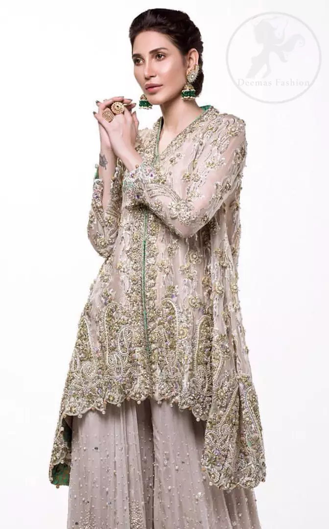 This sides down short frock is decorated with kora, dabka, tilla, sequins and pearls. It is embellished with floral embroidery. It is further enhanced with embroidered scalloped border which adds to the look. It comes with sharara which is adorned with floral motifs all over it. It is beautifully coordinated with chiffon dupatta which is sprinkled with sequins all over.
