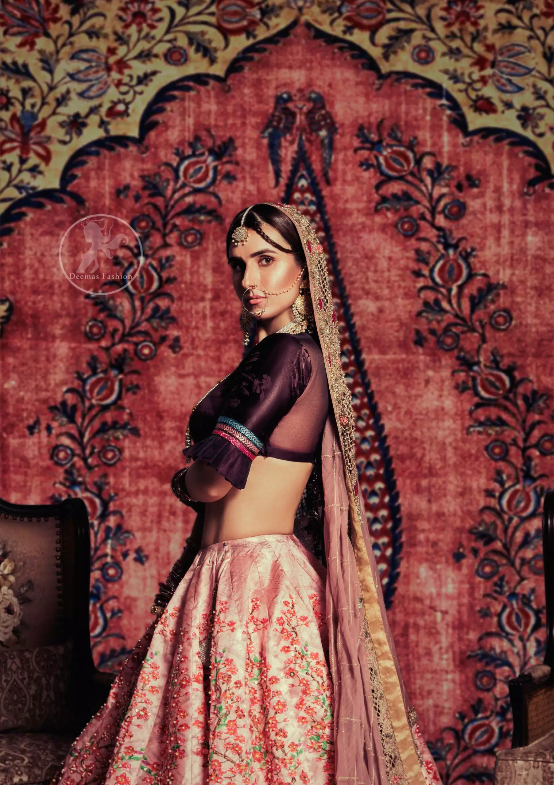 This outfit is a timeless beauty. Dark purple self-printed blouse is decorated with applique. The raw silk classic lehenga is adorned with digital print. Its floral print is further decorated with swarovski, tilla, kora dabka . Its beautiful printed border adds to the look. This outfit is beautifully coordinated with peach pink dupatta with heavy embroidered borders.
