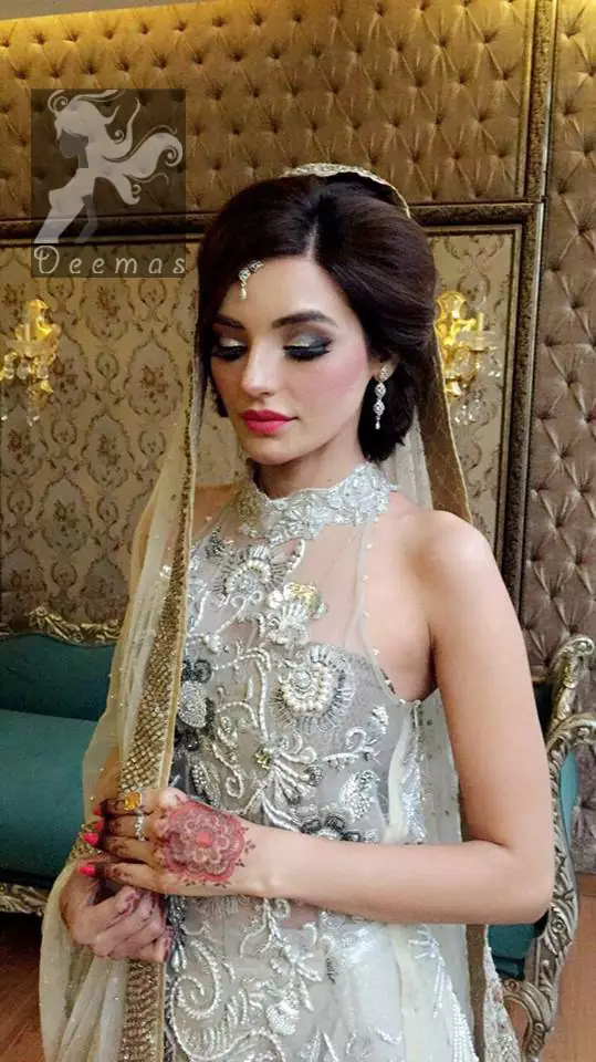 This outfit is a timeless beauty. It is heavily embellished with silver kora, dabka, sequins and swaronski crystals. This exquisite A-line frock is fully decorated with floral motifs patterns all over it. It is further enhanced with halter neckline.It comes with sharara which has small sized sprinkled floral motifs all over. This Outfit  is beautifully coordinated with matching dupatta with heavy embroidered borders and finished with piping.