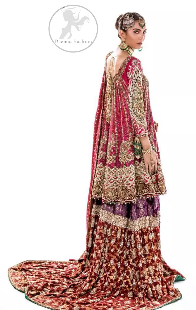 This bridal dress is adorned with floral embroidery.It is meticulously highlighted with dull golden and antique shaded kora, dabka, tilla, sequins and pearls. It has beautiful embellished bodice and U-shaped neckline which adds to the look.Sleeves are embellished with embroidered applique. Hemline is adorned with beautiful tassels. It is artistically coordinated with brocade embellished gharara. Gharara is allured with beautiful contrast of rust and plum color. It comes with pink dupatta which is decorated with embroidered borders and sprinkled sequins all over.