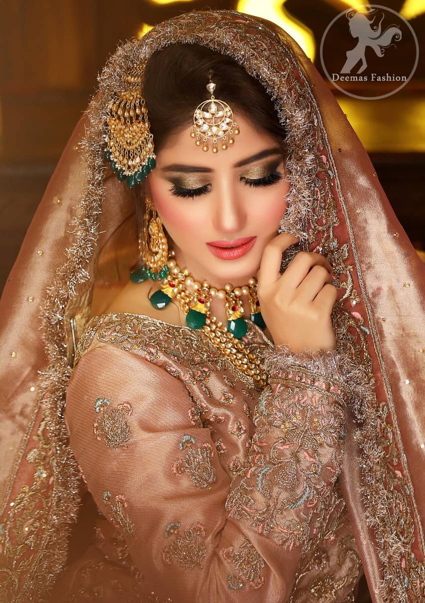 Feel glamorous in antique brass short shirt with fascinating embellishment on neckline with golden kora dabka, tilla and pearls. Floral motifs on sleeves add to the look. It is stunningly coordinated with traditional golden gharara. Complete the look with tilla work organza dupatta finessed with embroidered borders.