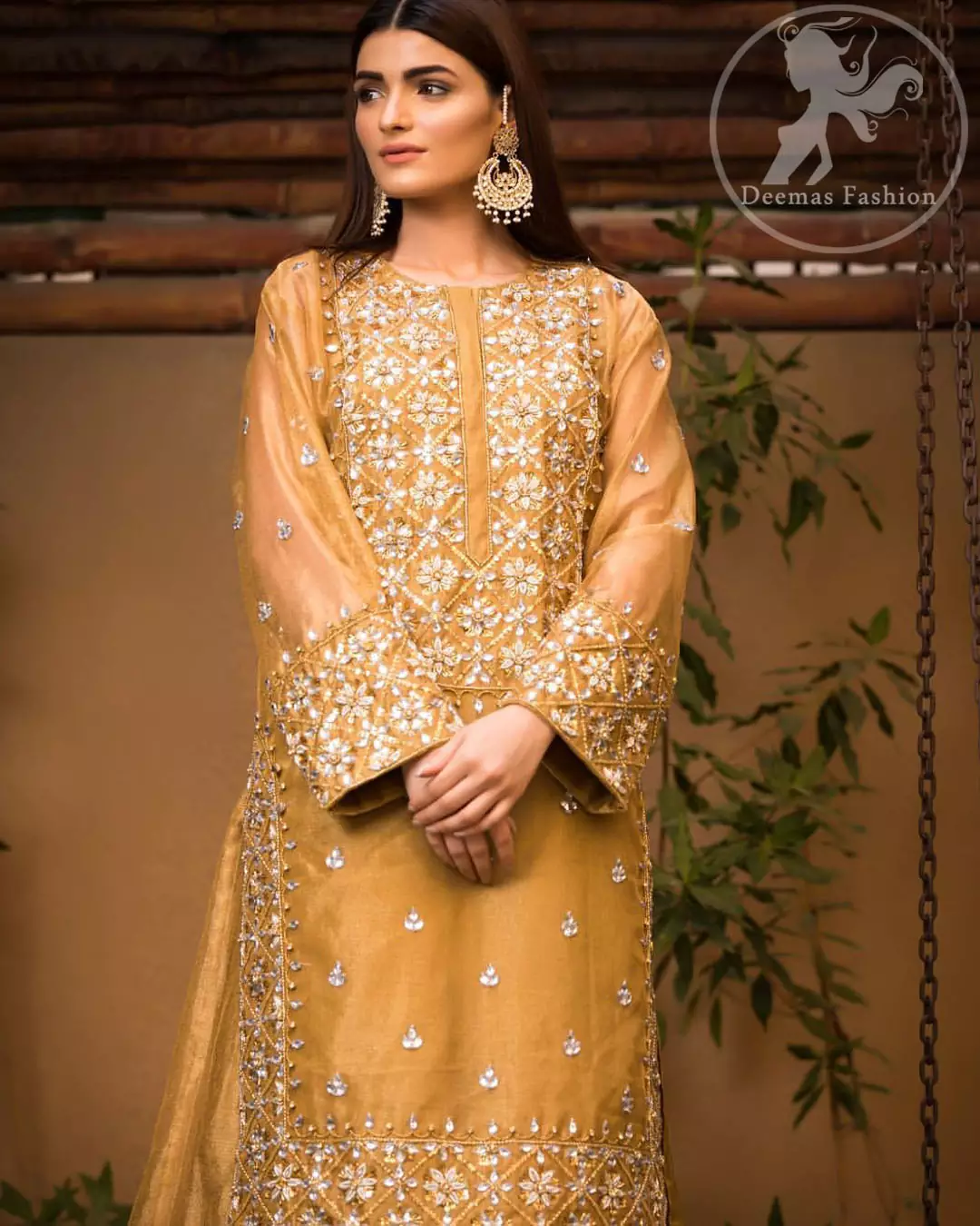 This dress is allured with floral embroidery. It is further enhanced with gota, kundan, sequins and pearls. It comes with organza lehengha. It is artistically coordinated with velvet shawl, having four sided embellished scalloped border.