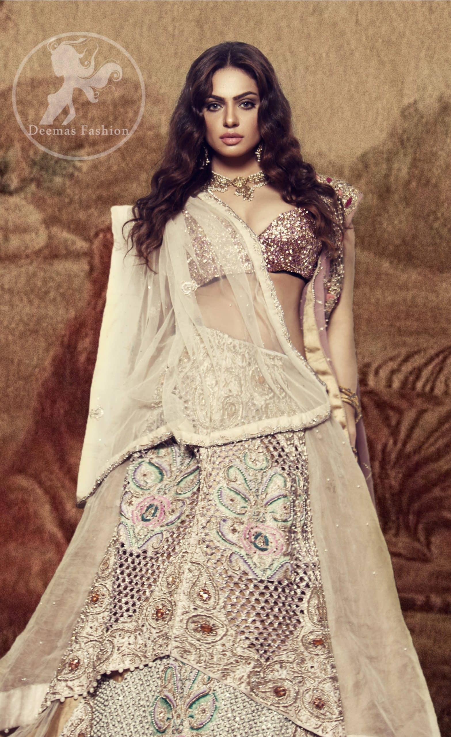 The bridal stands out due to its uniqueness and the perfect fusion of modern cut and traditional embroidery. This dress is beautifully decorated with heavy embroidery. It is highlighted with kora, dabka, tilla, sequins and pearls. It comes with embroidered sharara. It is coordinated with tissue dupatta which is sprinkled with sequins all over it. It is further furnished with four sided scalloped border.