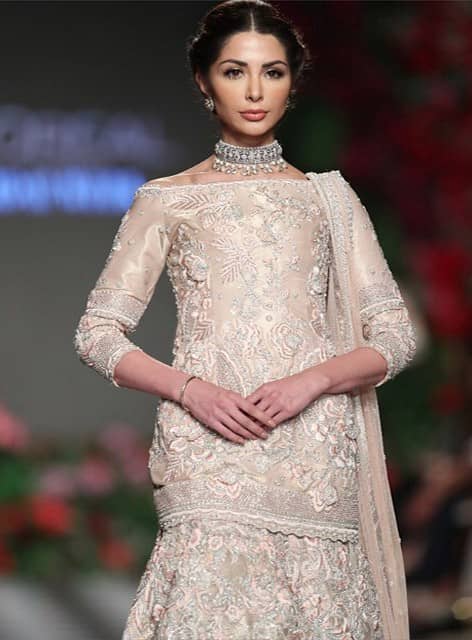 Capture the attention in this off shoulder tissue shirt with gold kora, dabka and kundan embroidery on the front. It is also enhanced with floral thread embroidery and finished with lace on the hemline. It comes with embroidered banarsi sharara. Sharara comprises of floral thread embroidery adorned with thick embellished border. It is paired with an ethereal dupatta focusing on kora and dabka handwork borders on all four sides.