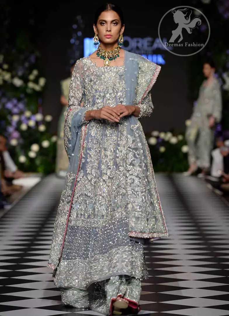 Boost your confidence and style in this glamorous attire accentuated with finest zardosi work embroidery and cut work neckline. It is beautifully decorated with heavy embroidery. It is highlighted with silver kora, dabka, tilla, sequins and pearls. It comes with heavily embroidered lehenga which is decorated with red piping from the bottom. It is coordinated with tissue dupatta which is sprinkled with sequins all over it. It is further furnished with four sided embellished border.