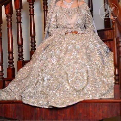 The grand gold bridal stands out due to its uniqueness and the perfect fusion of modern cut and traditional embroidery. This dress is beautifully decorated with heavy embroidery. It is highlighted with kora, dabka, tilla, sequins and pearls. Style it up with embellished wait belt. It comes with brocade pajama. It is coordinated with tissue dupatta which is sprinkled with sequins all over it. It is further furnished with four sided thick embellished border.