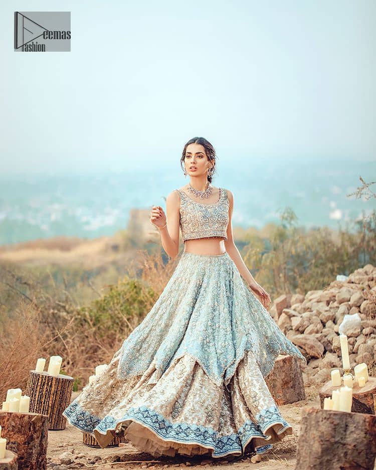 This bridal dress executing heavily hand crafted art of zardosi, kora and dabka with splashes of golden and silver is a classical visit to feminine personification. The heavenly handcrafted lehenga showcases the traditional art of zardozi, nakshi, kundan, kora and dabka; adorning the intricate and meticulous hand embellishments giving it a wholesome gentle stance paired with a regal gold sleeveless blouse. The bottom of the lehenga is enhanced with embellished applique with zardosi work and resham embroidery. It comprises with organza dupatta having four sided matha patti style border and scattered sequins all over it.
