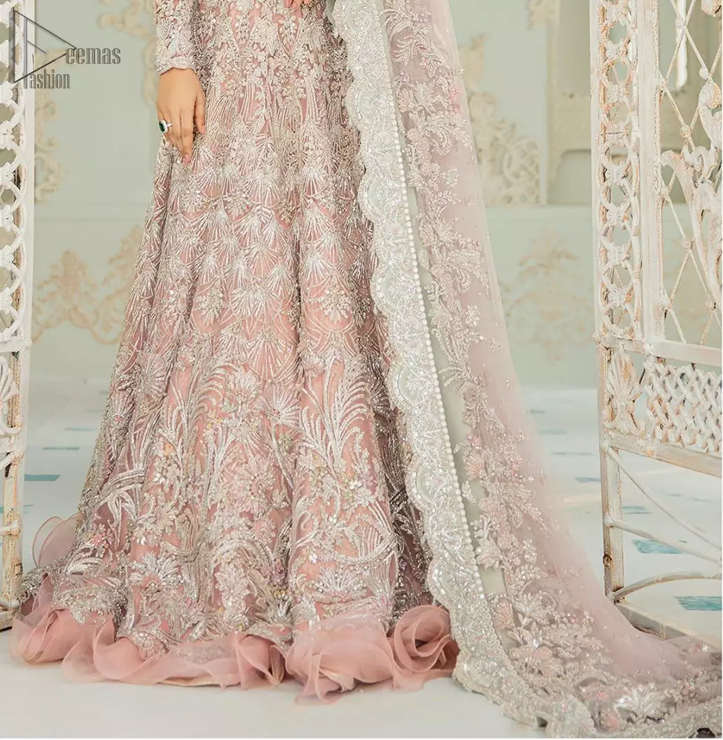 An example of beauty and elegance. Look breathtakingly stylish in this embroidered regalia furnished with intricate embroidered neckline. This ethereal maxi highlights the collision of heritage and beauty of traditional zardosi craftsmanship with modern chic silhouette. Beautifully designed sleeves is an amalgamation of geometric and floral design elements. The light pink net dupatta with chann and scalloped applique border all around the edges makes the look complete.