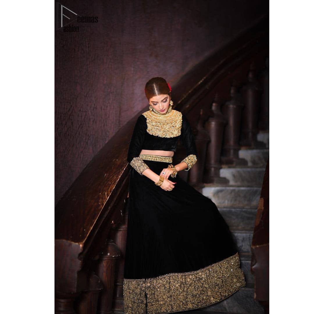 Embrace the season of festivities with this beautiful dress. This elegant ensemble turns timeless piece into a chic fantasy. The halter neck blouse is delicately hand crafted using the finest old age techniques and materials including kora, dabka, tilla, sequins, stones, and crystal. The sleeves are embellished with a thick embroidered border. Lehenga comprises of thick embroidered bottom to give it a regal look. It comes with a black net dupatta with sequins sprayed all over it .