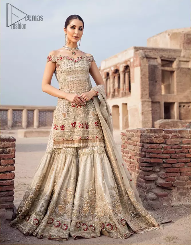 Classic and elegant, this dress is perfect for brides looking for a traditionally wedding outfit.. A perfectly pretty combination of light golden and antique embellishment, This off shoulder wedding dress is elegant and eye-catching in equal measure. This off shoulder shirt is done with zarozi detailing and vibrant floral motifs all over. Furthermore it is sculptured with different motifs like birds. It comprises with traditional handcrafted gharara. Complete the look with off white organza dupatta having four sided heavily embellished border and tassels.
