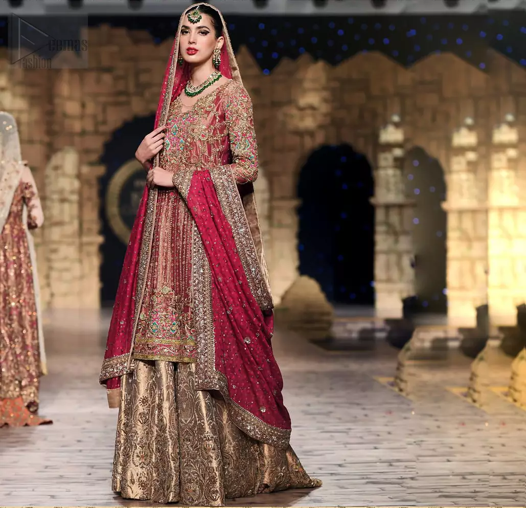 Nothing speaks of femininity and class louder than this outfit. This beautiful dress comes with burgundy A-Line frock with beautiful embellishment around the hem and vertically worked gold lines and it finished with a thick embellished border. The embroidery is done with golden, solver and antique shaded zardozi work. Furthermore it is also enhanced with multiple color thread embroidery in the floral motifs. Style it up with golden brocade sharara done with antique zardosi work at the bottom. This beautiful dress is comprises with burgundy dupatta sprinkled with sequins spray and four sided embroidered border.