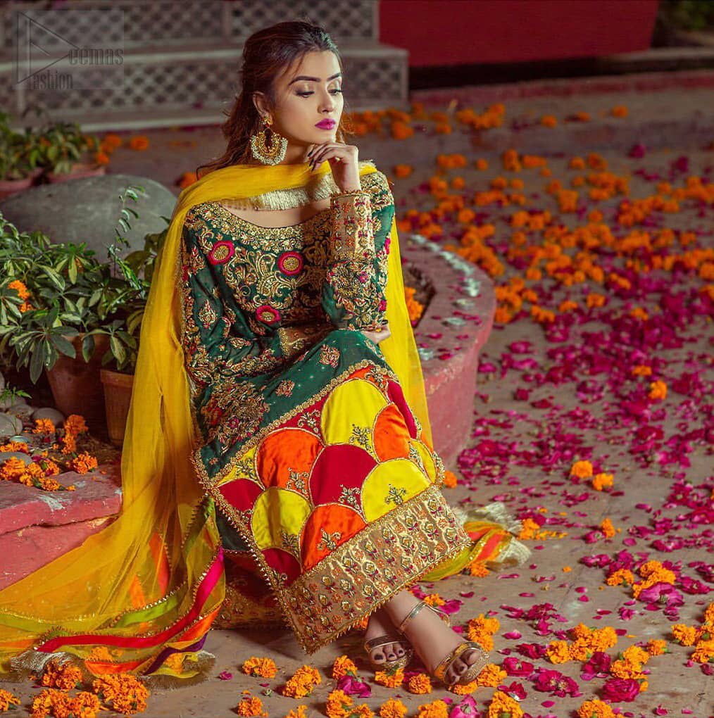 Beautifully elegant with a modern twist. This beautiful outfit comes with bottle green long shirt and colorful applique hemline, making an elegant, traditional and stylish mehndi dress. Excellence of craftsmanship is evident with intricate geometrical detailing that features the use of kora, dabka, crystals, sequins and glass beading. Furthermore it is enhanced with colorful floral motifs and golden zardozi work. It comprises with pink capri pants. Elegance is personified when it gets paired up with net dupatta with kiran on all sides and colorful strips on pallu.