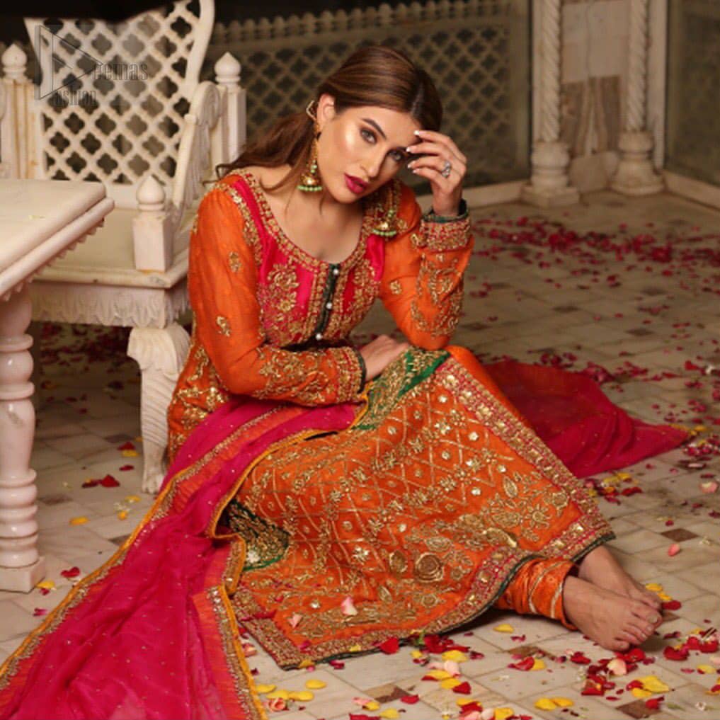 Get bold and beautiful with this uber-stylish ensemble that has flattering cuts, and a colour palette that is bewitching. This orange long shirt adorned with intricate tilla work, kora, dabka and sequins is perfect ensemble for mehndi. Furthermore the shirt is also highlighted with pink embellished bodice and rest of the shirt is enhanced with geometric gota embroidery and green applique instantly draws attention.. It comprises with orange pajama adorned with gota work. Paired with pink chiffon dupatta with kiran lace finishing all around the edges that gives the right amount of glamour to the outfit.