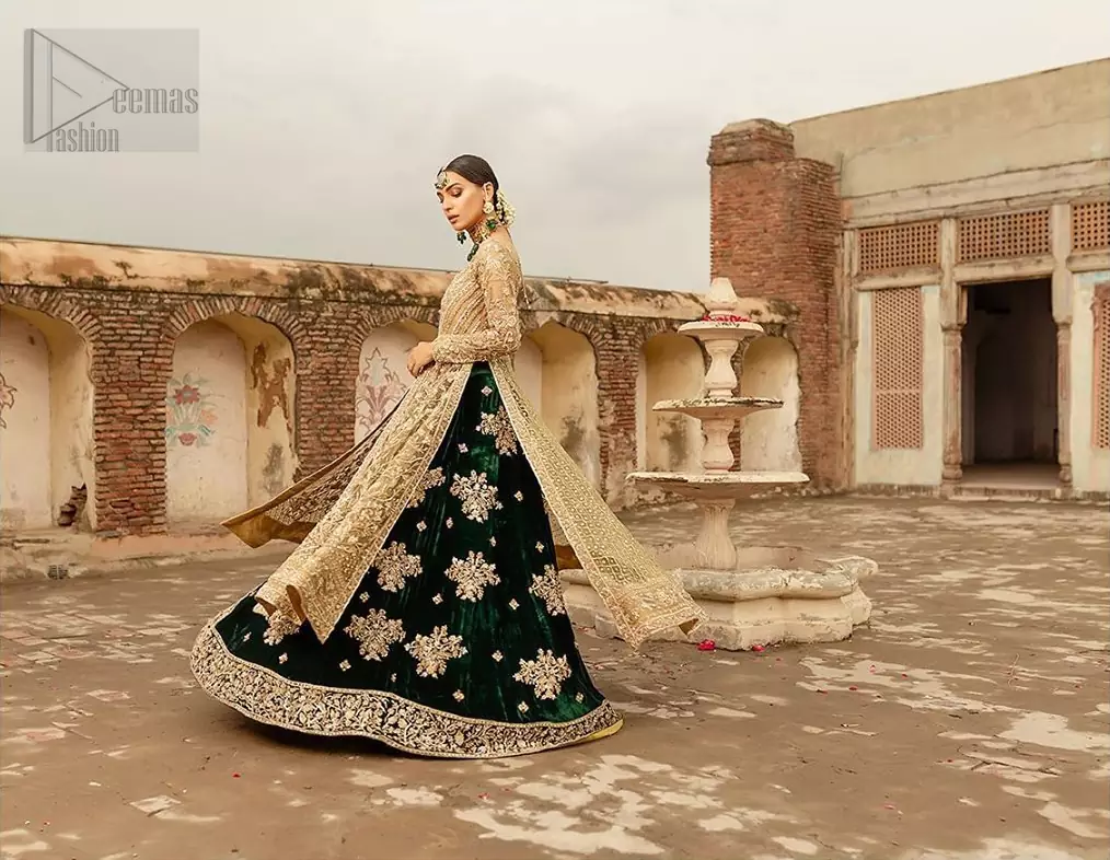 The new season is all about making a statement. Make your moment memorable being a queen in our fawn front open pishwas intensified with voguish sleeves, floral pattern all over and finished with thick embroidered border. The back of the shirt is also enhanced with criss cross patterns filling with beads. Pair it up with bottle green velvet lehenga emphasized with scattered floral motifs and intricate zardozi detailing at the bottom. Dupatta is decorated with vintage froral and finished with embroidered scalloped border on four sides which makes this outfit more beautiful.