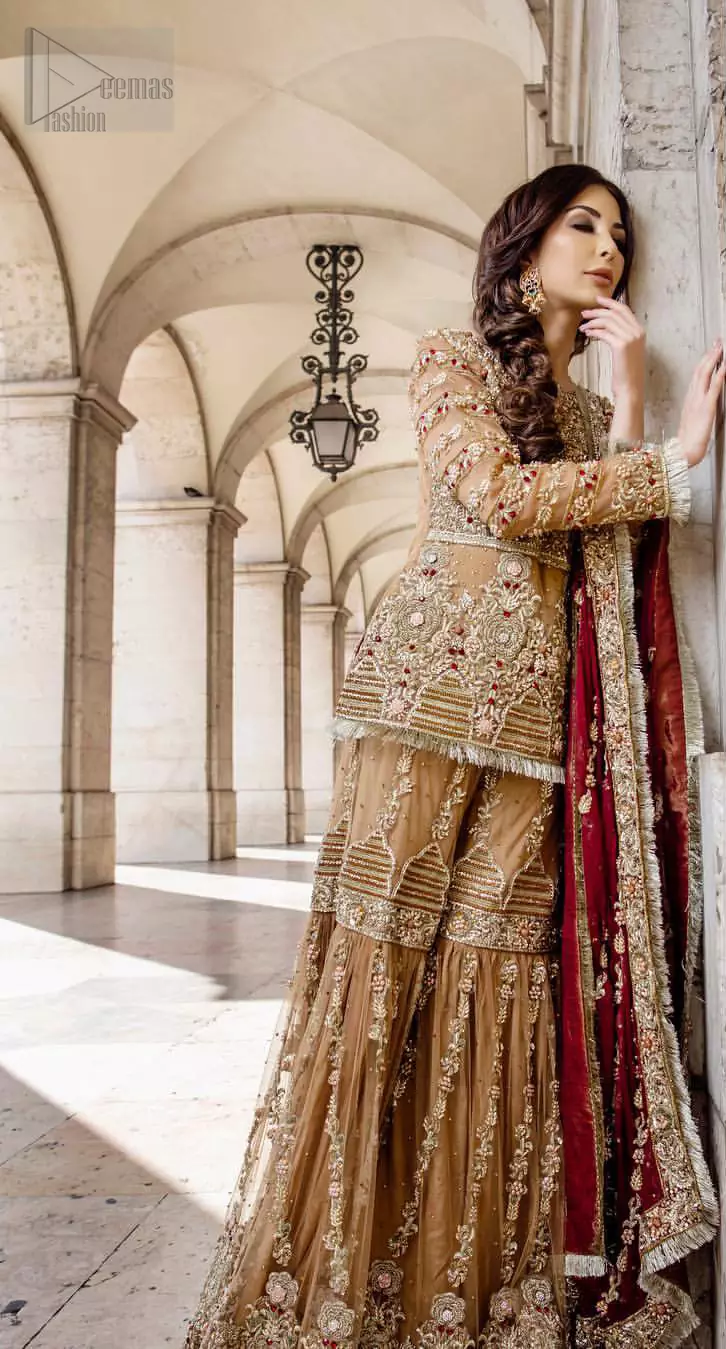 Picturing your bridal in a glowing fawn color. Featuring beautiful handwork, this outfit has a delicate arrangement of hand embellished geometric patterns with pearls and crystals on the bottom. Refined craftsmanship is at its best with hand embellished bodice which is laden with zardozi work. This outfit is paired with organza gharara with embroidered bottom and kiran lace, and maroon dupatta ornamented with geometric patterns along the length, making it a statement piece. Furthermore it is also enhanced with kiran lace on all four sides.