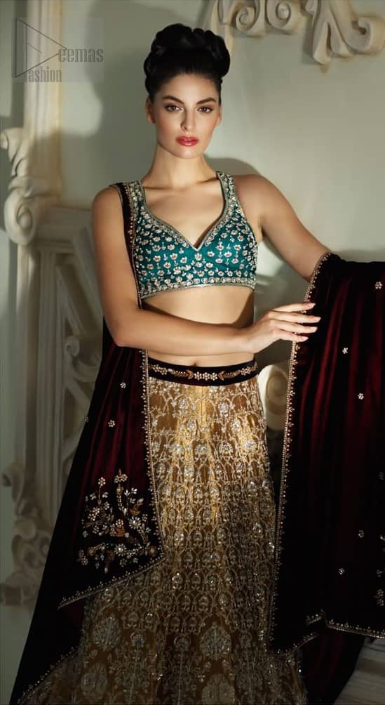 Delicately crafted and personifying chic elegance with an element of grandiose. Gussy up in this luxuriously designed lehenga blouse emboldened with intricate embroidery along with beautiful rich patterns and delicate details at the bottom. The maroon waist belt on lehenga make it so classy. It comprises with teel blouse adorned with tiny floral motifs in the shade of silver. The outfit is pair up with maroon velvet dupatta emphasized with silver and golden zardozi work on all four sides.
