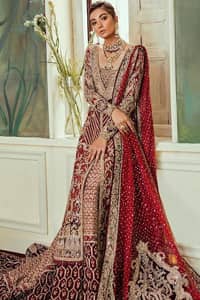 Chic, sleek and undeniably romantic, this beautiful deep red gown might just be the one for you. With pure fabric heavily laden with zardozi and the perfect blend of traditional flamboyance and modern elegance in design, you need to look no further for the perfect look for your special day. The bodice is heavily decorated with zardozi work, the rest of the gown is enriched with floral bootis and finished with the thick embellished bottom. Complete the look with an artfully coordinated lehenga which is ornamented with geometric patterns and captivating back trail design with traditional intricate embroidery. The outfit is coordinated with an organza dupatta finessed with embroidered borders.