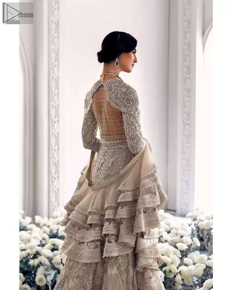 Your wedding day becomes more memorable when the guests are stunned by your majestic beauty and the perfect arrangements that are made. The Cream Lehenga Blouse is designed with such dexterity as to make you one gorgeous-looking bride on your big day. The dress code demands a full-sleeved blouse with a unique sweetheart neckline. Its exquisite fawn color is meritoriously adorned with superb silver embroidery and stylish tassels, which are indeed the most graceful works of matching embellishment. When it comes to the definition of elegance, the purest organza is specifically reserved for the creation of such marvelous attire. Followed by a beautiful dupatta and a lehenga, this charming bridal wear will make your Walima or Nikkah a heavenly day.
