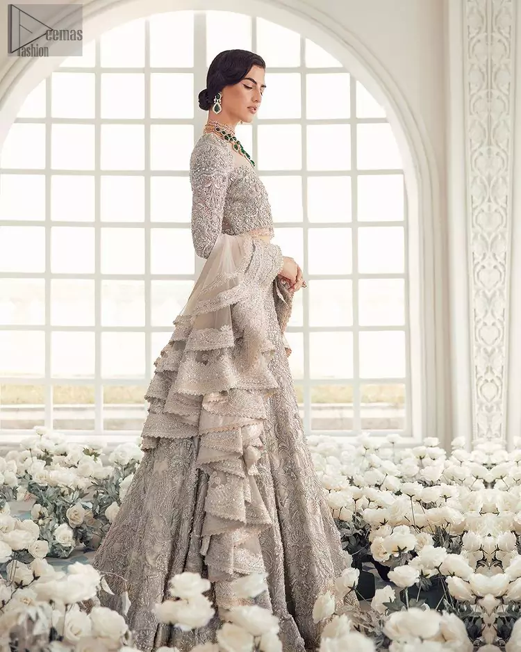 Your wedding day becomes more memorable when the guests are stunned by your majestic beauty and the perfect arrangements that are made. The Cream Lehenga Blouse is designed with such dexterity as to make you one gorgeous-looking bride on your big day. The dress code demands a full-sleeved blouse with a unique sweetheart neckline. Its exquisite fawn color is meritoriously adorned with superb silver embroidery and stylish tassels, which are indeed the most graceful works of matching embellishment. When it comes to the definition of elegance, the purest organza is specifically reserved for the creation of such marvelous attire. Followed by a beautiful dupatta and a lehenga, this charming bridal wear will make your Walima or Nikkah a heavenly day.
