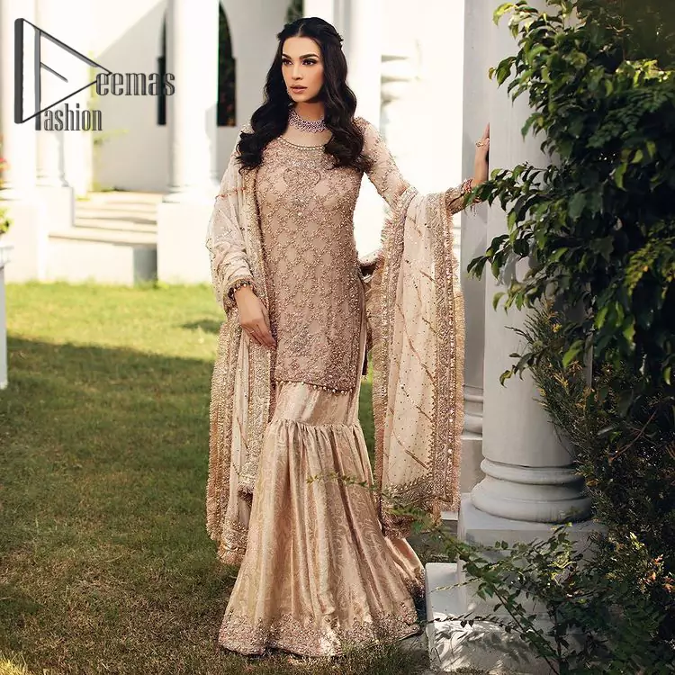 Opt for a versatile outfit for your Nikkah that is the perfect amalgamation of splendid colors, deluxe fabrication, and exquisite profile as well. Satiate your soul with extraordinary ensembles from this fawn long shirt gharara of DeemasFashion outfits. The round neckline of the long shirt is just amazing when combine with full sleeves. Further, it is highlighted with golden embroidery that includes tilla, kora, and dabka work. Pair up it with fawn gharara made with pure Katan banarsi jamawar fabric just to grant you a super aesthetic look. Complete this outfit with a fawn dupatta that is embellished with a four-sided Kiran and border as well.
