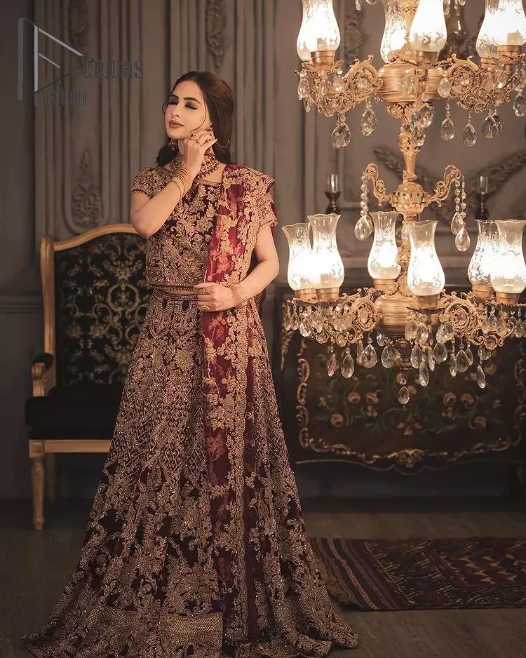 With the right outfit, every bride can rule the world! As nothing makes a bride more beautiful than the trust of her outfit. Introducing maroon half sleeves blouse that is fully embellished with tilla, kora and dabka work. In addition to this, the boat shape neckline of this blouse that is made with pure velvet gives you a dreamy look. It is synchronized with a velvet lehenga that is adorned with priceless heavy embroidery. Finish this look with an organza dupatta, embellished with embroidered scalloped borders to give you a relaxing and soothing look at your reception.