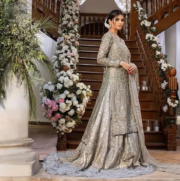 Gratifying yourself with the choice of the right dress is not always easy. But with a full-sleeved Gray Back Train Ruffled Lehenga Shirt, you would be more than pleased with your perfect decision. Marvellous back train, gorgeous round neckline, stunning frilled edges, outstanding geometric patterns and beautiful matching embellishment, this delightful bridal wear is truly a progressive contribution to your decent personality. The dress code features a grey admirable shirt and dupatta made with pure organza, and a graceful lehenga made with katan banarsi jamawar. A concluding work of extreme exquisiteness in the shape of silver and gold embroidery over the dress, finally makes this attire ready to serve you with utmost satisfaction on your walima or nikkah day.
