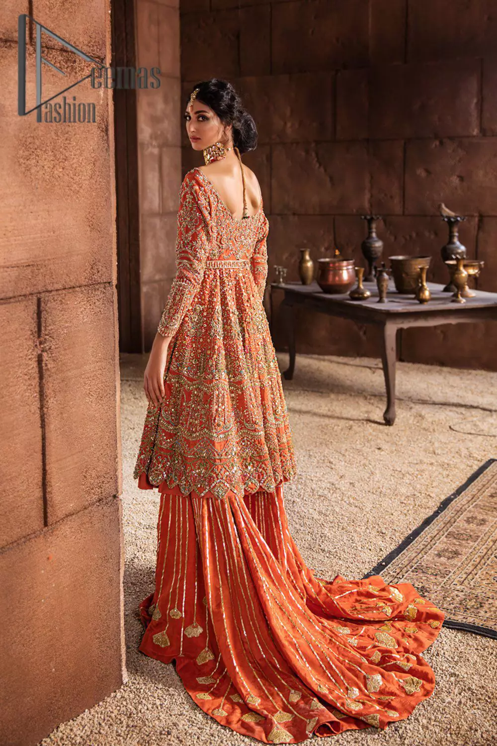 Fall in love with elements of detailing. Embrace your Mehandi style story with this orange attire serving vogue at its best. This orange frock is attractively adorned with golden embroidery that is further highlighted with kora, dabka, tilla, and antique work. And the scalloped border of the frock is just amazing so you can steal everyone’s heart. In addition to this when the boat shape neckline combines with full sleeves it gives a super aesthetic scene. It is beautifully paired up with back train sharara that makes you a focus star of the day.
