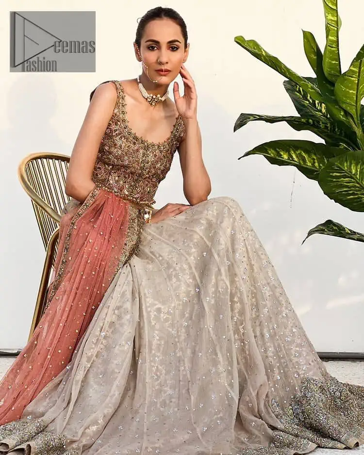 The perfect outfit for walima to enhance your glow. Starting this article with a dream rust blouse having a strap neckline and prominent sleeveless style to embrace the romantic culture. The following blouse is fully embellished with golden embroidery that is prominent with tilla, dabka, kora, pearls and sequins spray to fulfil your dreamy look. It is coordinated with an ivory can-can lehenga whose border is again rendered with golden embroidery and sequins sprayed all over to continue the look. Complete this outfit with a rust dupatta which is embellished with four-sided borders and sequins sprayed all over to enhance the glow of the bride.