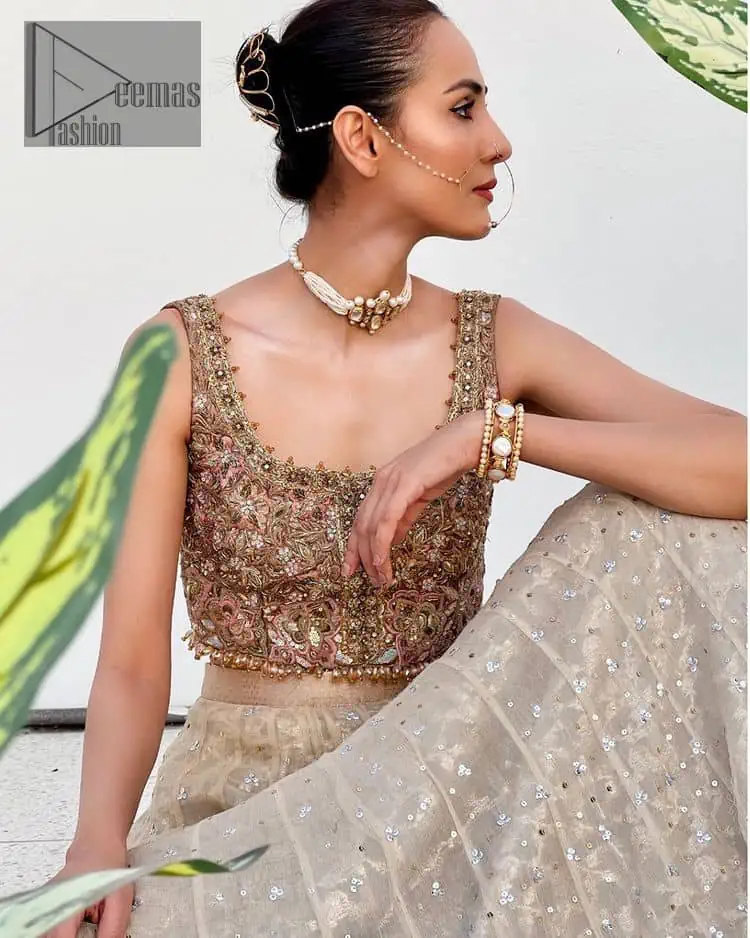 The perfect outfit for walima to enhance your glow. Starting this article with a dream rust blouse having a strap neckline and prominent sleeveless style to embrace the romantic culture. The following blouse is fully embellished with golden embroidery that is prominent with tilla, dabka, kora, pearls and sequins spray to fulfil your dreamy look. It is coordinated with an ivory can-can lehenga whose border is again rendered with golden embroidery and sequins sprayed all over to continue the look. Complete this outfit with a rust dupatta which is embellished with four-sided borders and sequins sprayed all over to enhance the glow of the bride.