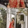 Feels just redish on your Big day to make your day lovely and romantic. DeemasFashion presents this Pakistani reception wear for you in bright red colour which begins with a flared back train maxi. The maxi is attractively and laboriously adorned with golden embroidery that enhances tilla,dabka, kora and Kundan. In addition to this, the boat shape neckline intensifies the beauty of this Pakistani reception wear when comes with full sleeves. The flared back train of the maxi is also heavily embellished. Complete this article with a dupatta in the same colour which is adorned with four-sided borders and tiny floral motifs, sequins spray all over to make you fresh on your Big day.