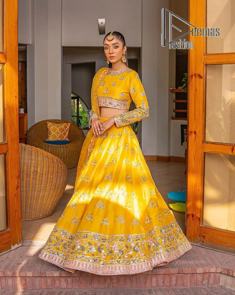 Yellow is just associated with mehndi as the sun is associated with brightness. DeemsFashion presents the bright yellow Pakistani mehndi outfit which laboriously begins with a blouse which is handsomely hand-rendered with silver and copper embroidery to make your day super duper bright. The boat shape neckline and full sleeves of this Pakistani mehndi outfit add to the breathtaking dream of the bride. It is paired up with a lehenga in the same colours which is adorned with floral motifs and bordered embroidery as well. Complete this Pakistani mehndi outfit with a dupatta in the same colour which is adorned with a four-sided embellished border and sequins sprayed all over.
