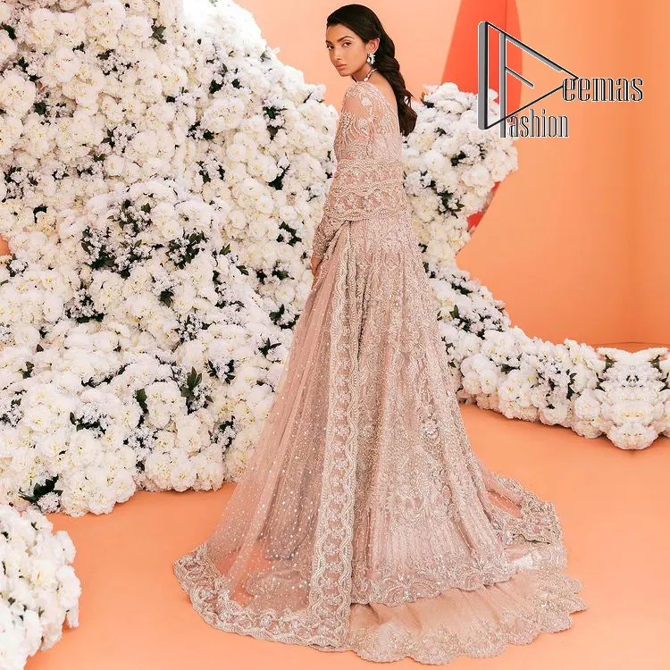 A magical evening, the moon reflects your face of you!  This romantic beige-pink front open maxi is laboriously decorated with silver embroidery to make your nikah dress super magical. The hand-rendered involves kora, dabka, tilla and crystal. Further, the V shape neckline and full sleeves of this nikah dress are as amazing as ever the bride wants on her day. It is coordinated with a back train lehenga which is specially designed with a scalloped style and also heavily ornamented with embroidery. Completed this Nikah dress with a scalloped dupatta in the same colour which is again embellished with four-sided borders and sequins sprayed all over to make your evening super magical.