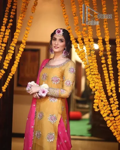 We seek outside the wonders we carry inside us. A mehndi dress in the mustard shirt is enhanced with gorgeous gota work. and is designed using the floral technique in pink and golden which is incrusted with tilla, dabka, kora and Sitara. The border of the mustard shirt is heavily ornamented with golden embroidery. The round neckline enhances the beauty of this mehndi dress when comes with three-quarter sleeves. It is paired up with mustard Gharara which is super simple and its border is encapsulated with Kiran. Complete this mehndi dress with a pink dupatta having ting floral motifs all over.