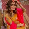 We seek outside the wonders we carry inside us. A mehndi dress in the mustard shirt is enhanced with gorgeous gota work. and is designed using the floral technique in pink and golden which is incrusted with tilla, dabka, kora and Sitara. The border of the mustard shirt is heavily ornamented with golden embroidery. The round neckline enhances the beauty of this mehndi dress when comes with three-quarter sleeves. It is paired up with mustard Gharara which is super simple and its border is encapsulated with Kiran. Complete this mehndi dress with a pink dupatta having ting floral motifs all over.