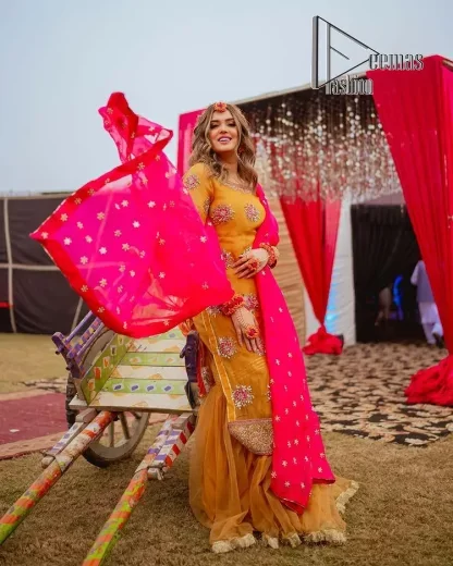 We seek outside the wonders we carry inside us. A mehndi dress in the mustard shirt is enhanced with gorgeous gota work. and is designed using the floral technique in pink and golden which is incrusted with tilla, dabka, kora and Sitara. The border of the mustard shirt is heavily ornamented with golden embroidery. The round neckline enhances the beauty of this mehndi dress when comes with three-quarter sleeves. It is paired up with mustard Gharara which is super simple and its border is encapsulated with Kiran. Complete this mehndi dress with a pink dupatta having ting floral motifs all over.