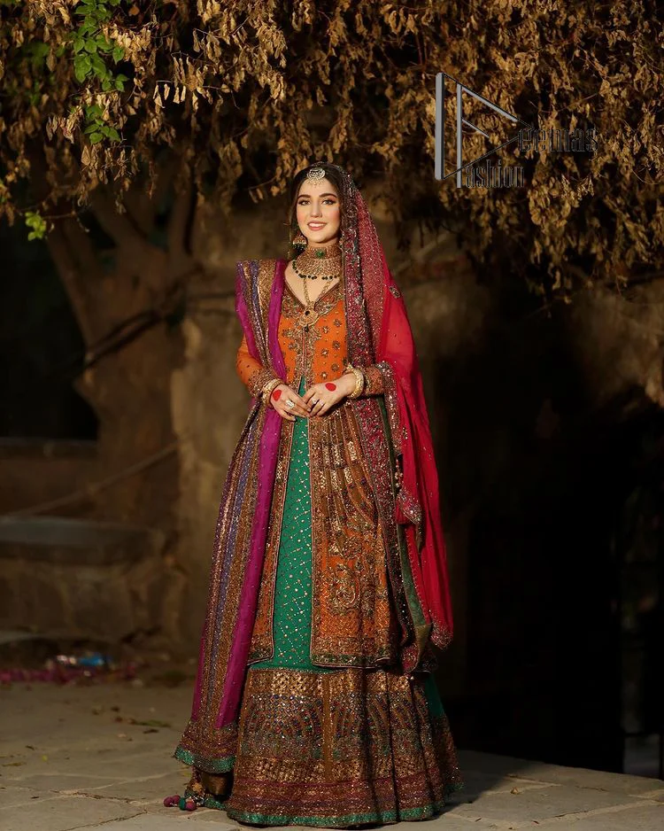 A colourful mehndi outfit is a power which directly influences the soul. Begin this mehndi outfit with a rusted front open shirt which is beautifully decorated with colourful embroidery to give you more power on your mehndi day. It is prominent with tilla, dabka, kora and zardozi. Further, the V shape neckline adds to this mehndi outfit when comes with full sleeves. Paired with a green lehenga having multiple colour borders to give you a more traditional look also. Complete this mehndi outfit with a colourful dupatta which is adorned with four-sided borders and sequins sprayed all over.