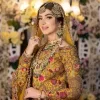 Take your style quotient up a few notches in this exquisite mehndi outfit! ]The maxi in mustard colour is a ravishing bridal attire with a magnificent elite and classy appearance. Gorgeous and glamorous multiple-colour embroideries enhance the showiness of this maxi.  It is further intensified with tilla, dabka, kora, Kundan and details of thread embroidery. Full sleeves, boat shape neckline and sparkling work make it a perfect traditional wear. It is coordinated with a scalloped dupatta in the same colour which is embellished with four-sided borders and floral motifs all over to make this outfit unique and aesthetic.