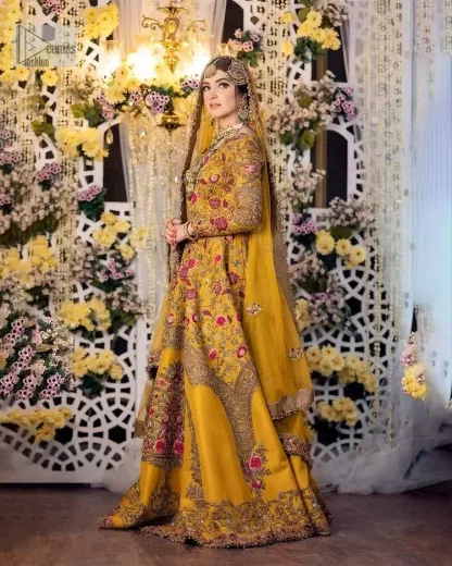 Take your style quotient up a few notches in this exquisite mehndi outfit! ]The maxi in mustard colour is a ravishing bridal attire with a magnificent elite and classy appearance. Gorgeous and glamorous multiple-colour embroideries enhance the showiness of this maxi.  It is further intensified with tilla, dabka, kora, Kundan and details of thread embroidery. Full sleeves, boat shape neckline and sparkling work make it a perfect traditional wear. It is coordinated with a scalloped dupatta in the same colour which is embellished with four-sided borders and floral motifs all over to make this outfit unique and aesthetic.