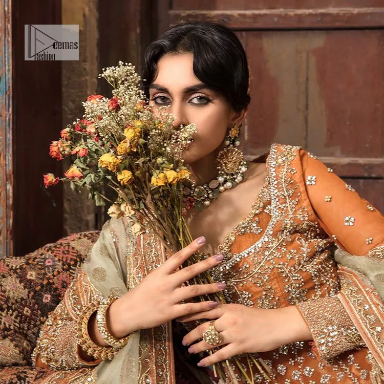 Let your dreams be your wings as your mehndi outfit. This rust heavy maxi features thoughtfully placed bold motifs all over and each motif is crafted using tilla, dabka, koran, Resham and Zardozi techniques. It is further enhanced with golden embroidery. The V shape neckline adds more beauty to the outfit when comes with embellished full sleeves. The beautiful outfit achieves the final ravishing look when paired with a delicate dupatta. The borders of this dupatta are heavily adorned with embroidery that gives a slaying touch to the whole attire.
