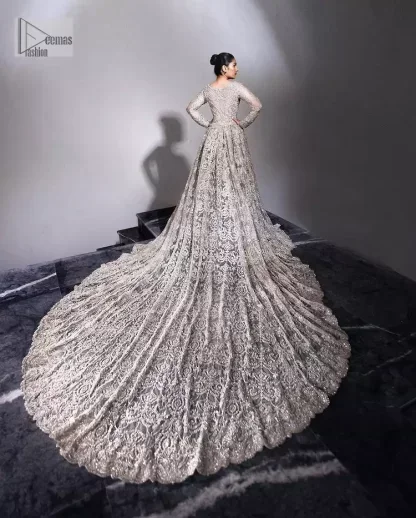 The trend of the back trains is still going strong as nikah wear - Here is the perfect one! This beautiful silver maxi is heavily embellished with silver embroidery. The gorgeous work of pearls, dabka, kora, Kundan and silver stones enhance the overall glamour of this maxi. The extraordinary design of the jewel neckline is completely embellished with silver stones and pearls embroidery combinations. The silver stones touch-up increases the looks of the beautiful gown with long tails that gives everlasting impact and at the bottom is the double flare. The full sleeves of the maxi are the lavishing style that any bride can wear on her big day.