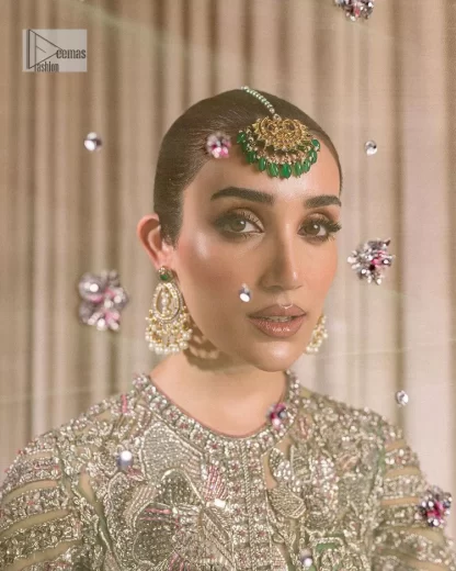Dive into the world of ultimate allurement with this exquisitely embellished Mehndi outfit that depicts intricate glam with an elegant statement detailing. The maxi in teal green colour is heavily adorned with silver embroidery which involves tilla, dabka, kora, Kundan and the real magic of Zardozi. Further, the high neckline and full sleeves add extra glamour to this outfit. It is organized with magnificent lehenga in the same colour emblazoned with intricate gleaming embroidery which enhances the charm of this Dress. The tiny floral motifs also spread on the lehenga. Complete this article with a dupatta framed with four-sided borders and tiny floral motifs all over to make your day charming.