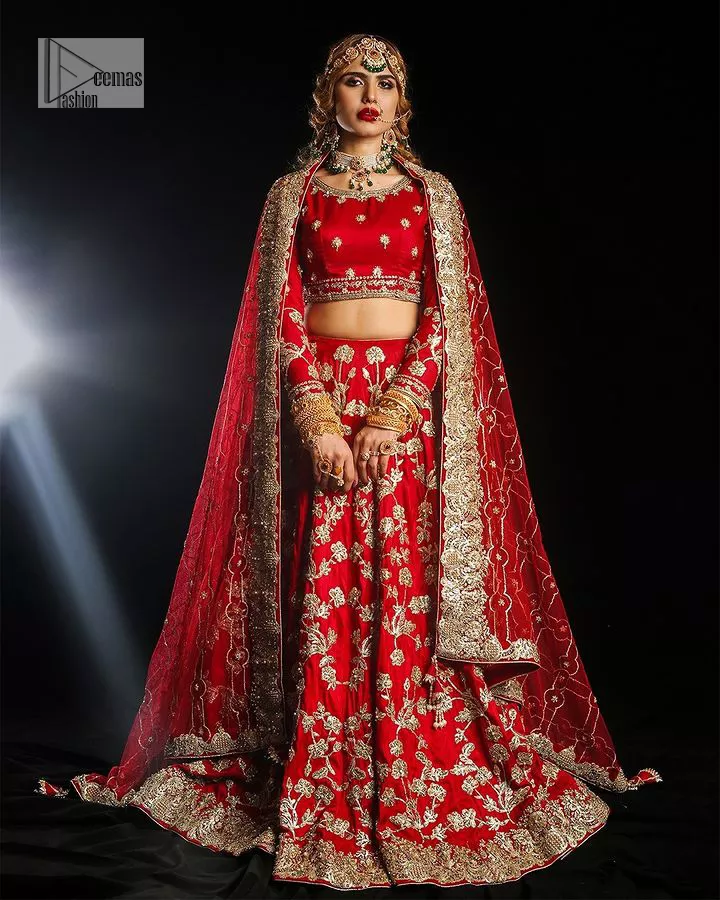Reception called, and red answered. The stunning blouse is embellished with floral motifs. The base colour used for choli is wine red.  The sleeves of the blouse are embellished with floral patterns to make this reception wear the epitome of beauty. Further, the boat shape neckline also adds super charm and beauty when paired with a lehenga. The lehenga is adorned with golden embroidery which is further enhanced with tilla, dabka, kora, Kundan and the real magic of Zardozi. Complete this romantic article with a dupatta framed with a four-sided embellished border to give a glamorous touch to this magnificent attire.