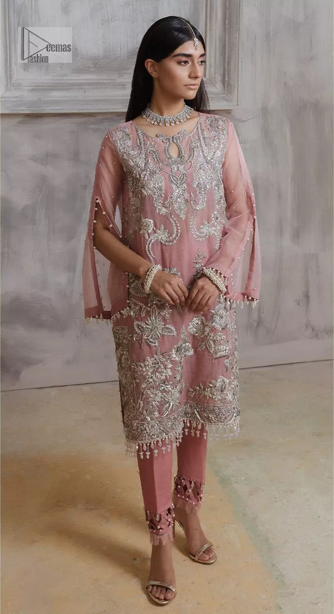 Make a style statement in this beautiful tea-pink canvas. The heavy shirt comes in a tea-pink colour and is gracefully emblazoned with silver embroidery. Hand-crafted details of sequins, tilla, dabka, kora and Zardozi give a glamorous touch to this beautiful party wear. Further, the crystalline hanging also makes this masterpiece unique and gives you a royal look. The round neckline also adds beauty to the outfit. It is paired up with trousers to balance the overall outfit.