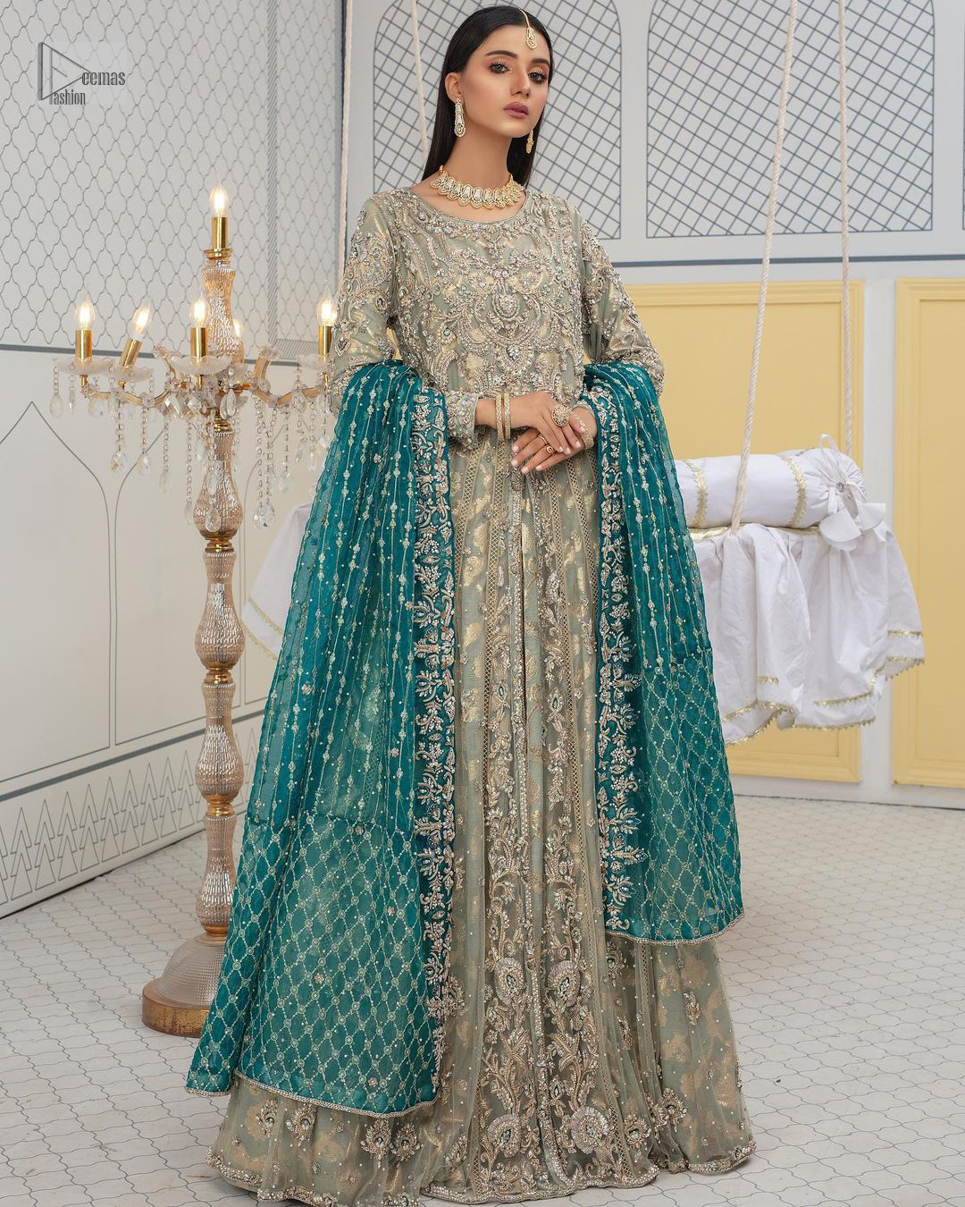 Embellishment is on the rise! The elegant front open maxi is heavily embellished in work of tilla, sequins, dabka, Zardozi, Kundan and kora work. The magnificent maxi is further highlighted with silver embroidery on the front and backside. Further, the full sleeves of the dress come with attractive embellishments. The round neckline makes this masterpiece more unique and charming. This nikah outfit is coordinated with a dupatta in teal green colour framed with a four-sided border and sparkling sequins all over that are on the peak in modern style.